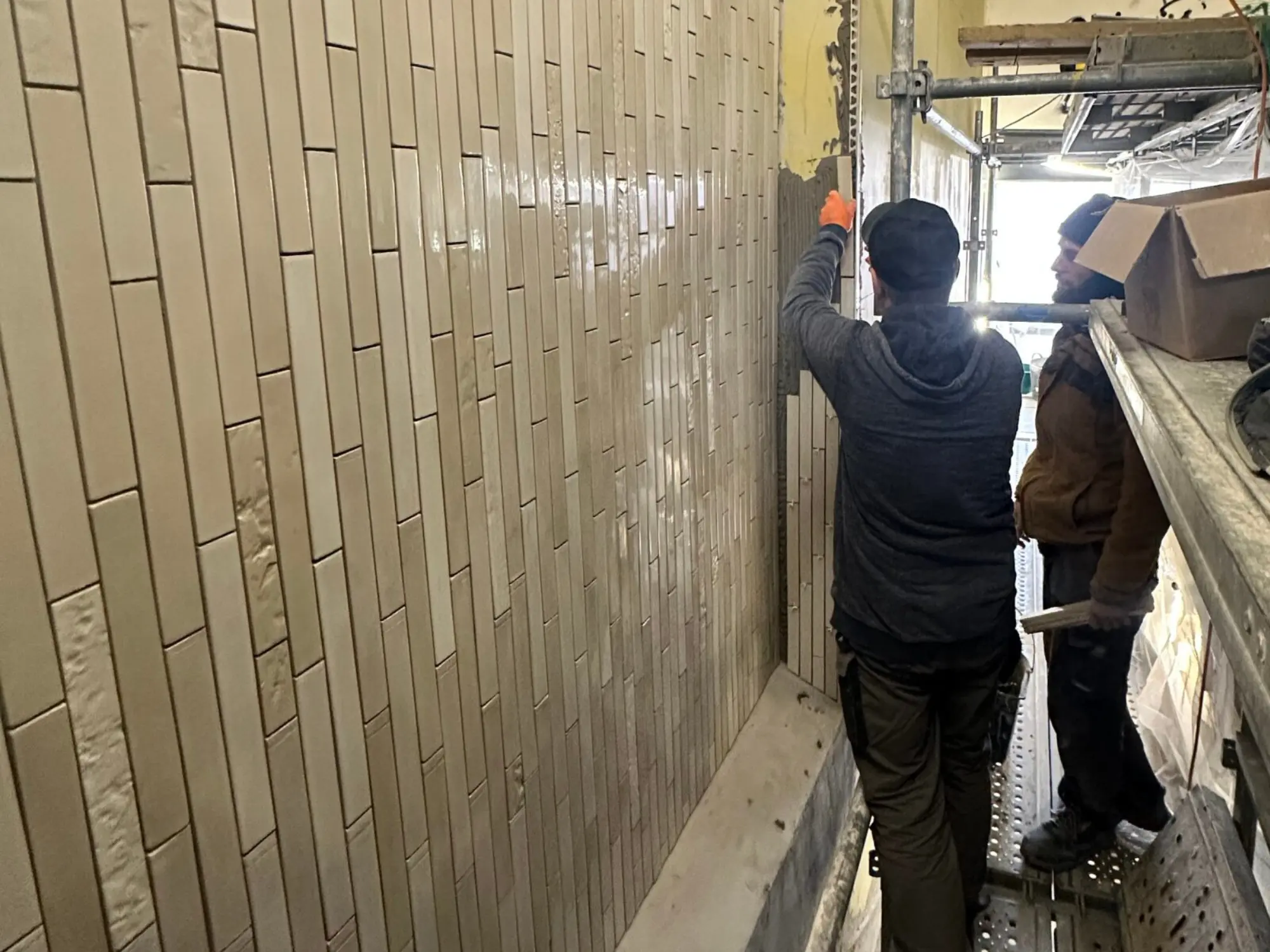 Transmission du savoir-faire entre compagnons carreleurs sur chantier en Île-de-France